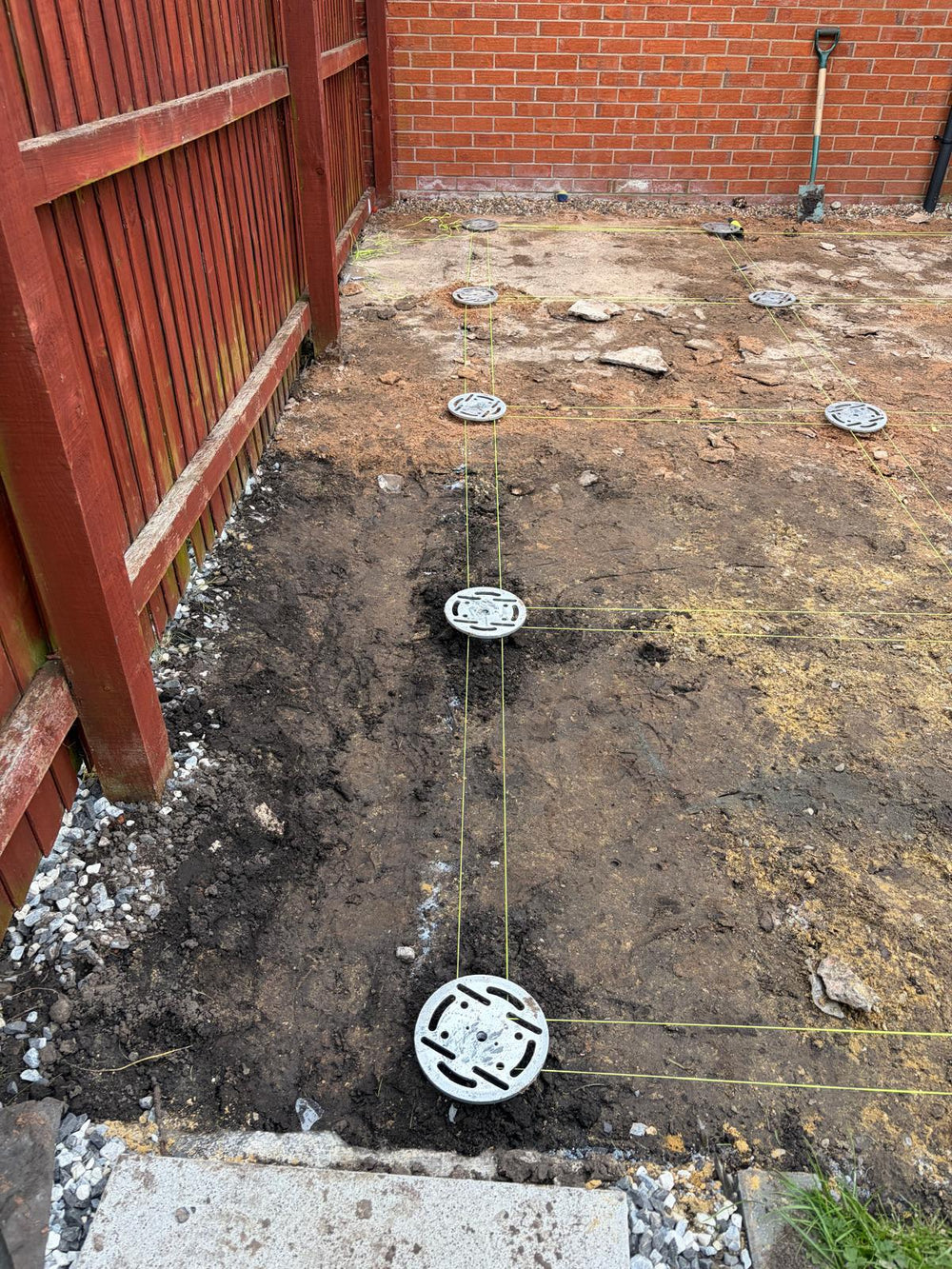 Ground screw foundations aligned with string lines on a prepared building footprint