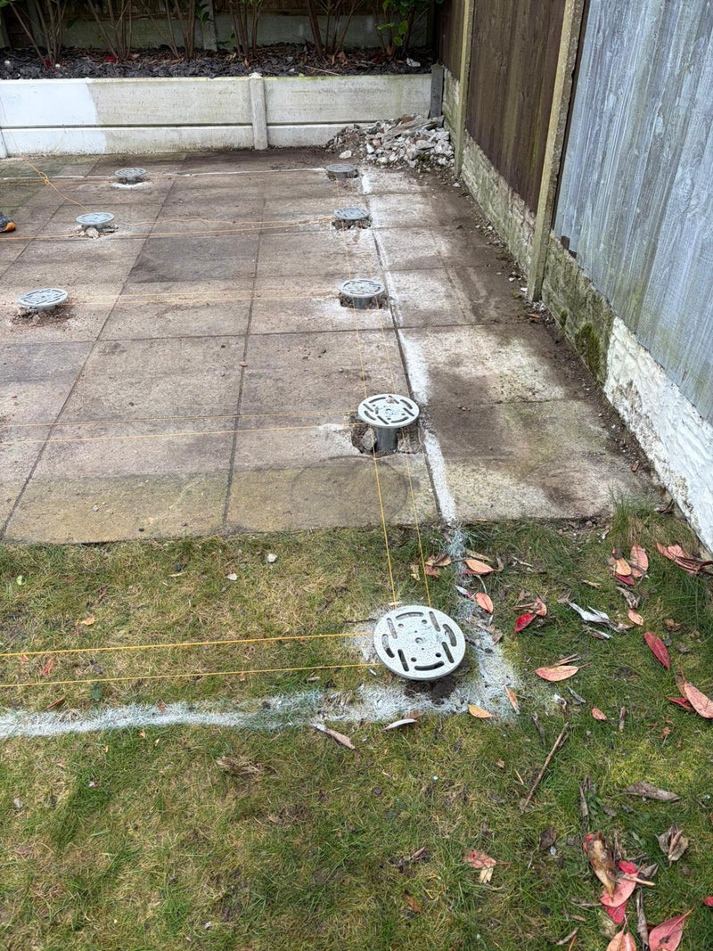 Ground screw heads and string lines set out through an existing paved area